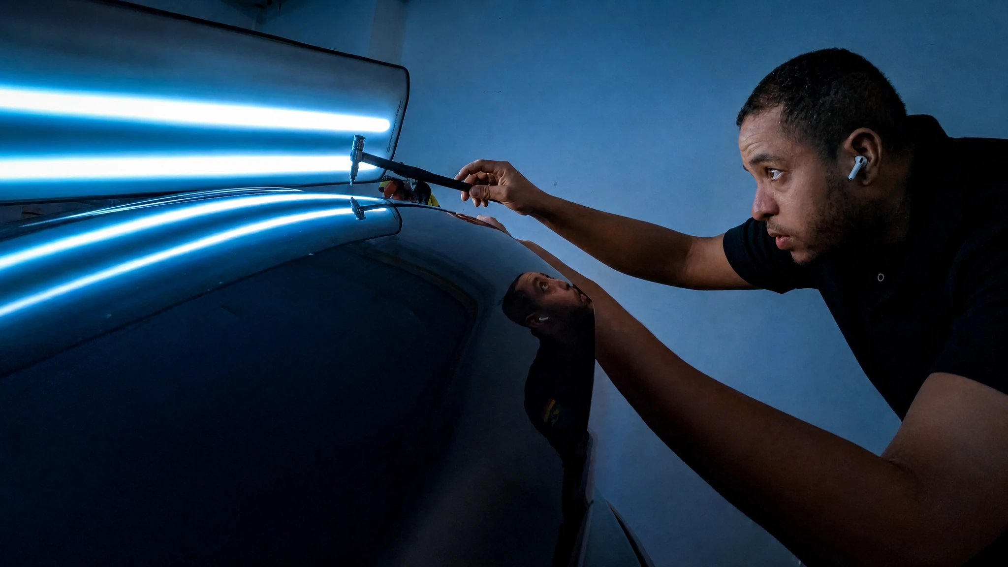 Fachmann bei der präzisen Dellenreparatur unter LED-Lichtleiste
